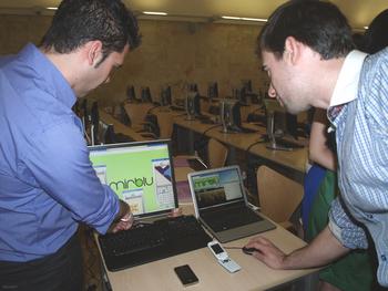 Los dos jóvenes emprendedores muestran su trabajo en el ordenador.