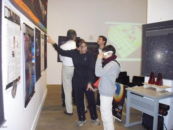 La responsable del expositor muestra los poster sobre astronomía en 3D.