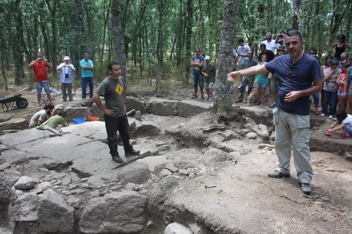 Rubén Rubio, a la izquierda, e Iñaki Martín Viso explican la cabaña con suelo de piedra a visitantes de la excavación.