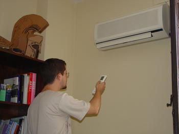 Un joven regula la temperatura del aire acondicionado
