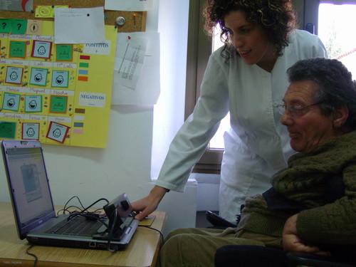 Un usuario del centro de día de Aspace utiliza un ordenador a través de su iris con el asesoramiento de una asistente.