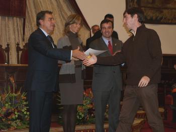 Uno de los premiados en el VII Certamen Universitario Arquímedes es felicitado por el consejero de Educación en presencia de la ministra.