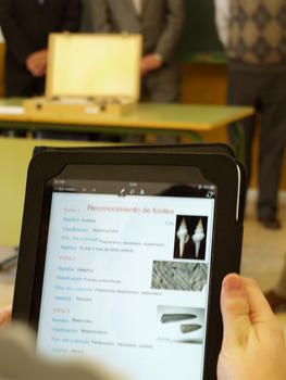 Presentación sobre fósiles en la tableta digital de un alumno, en el centro de educación obligatoria Miguel Delibes de Macotera (Salamanca). Al fondo, un maletín contiene algunos ejemplos.