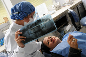 Una dentista muestra una radiografía de su dentadura a una paciente.