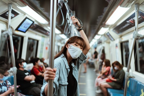 Una mujer con mascarilla viaja en transporte público.